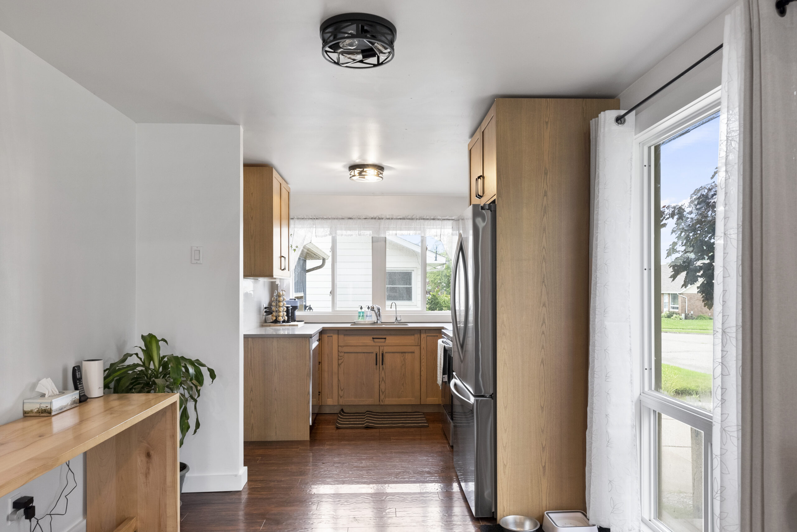 Galley kitchen with custom wood cabinets, white countertops, and stainless fridge