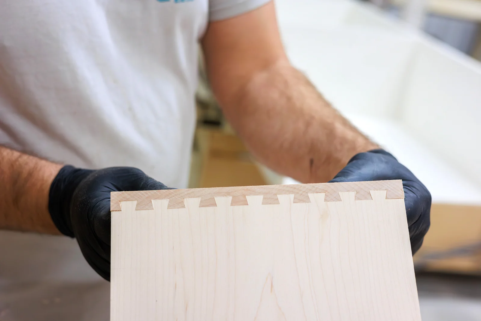 Close-up of a dovetailed wooden drawer component held in the workshop